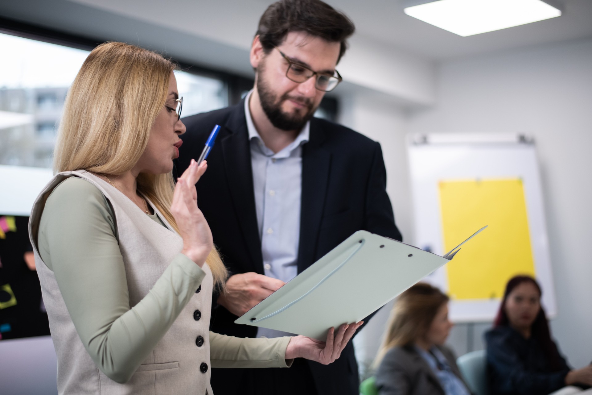 Colleagues discussing work and analyzing documents during a professional business meeting with a collaborative atmosphere in a bright office setting.
